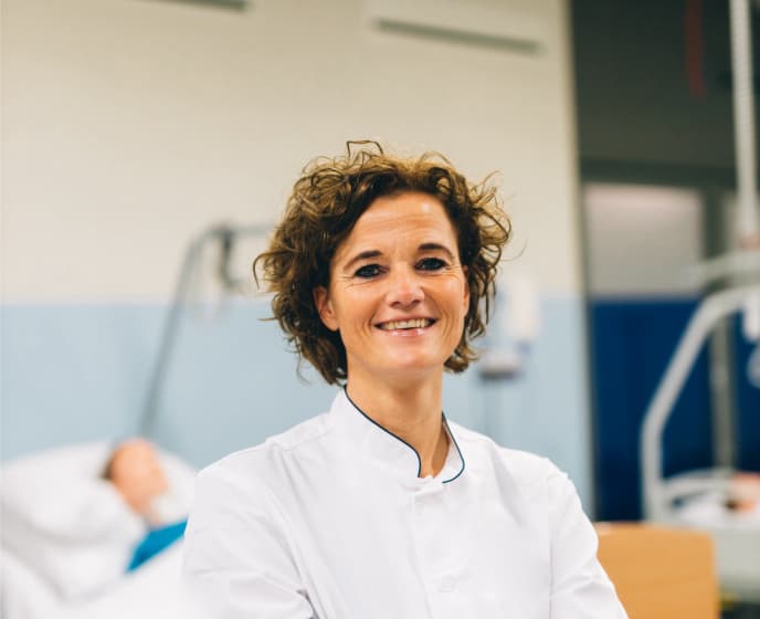 Zorgprofessional in witte jas glimlacht naar de camera